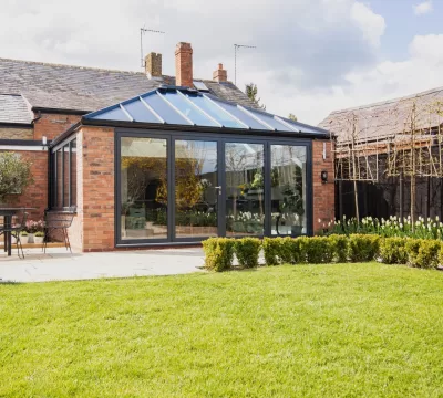 Back garden of home extension with brick walls and black window frames, an Ultraframe hup! extension
